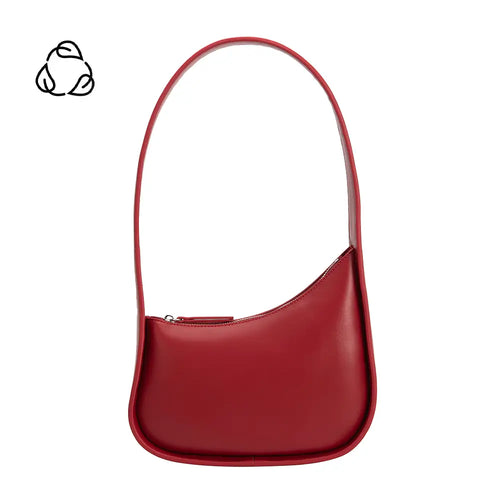 The Willow Recycled Vegan Shoulder Bag is a sleek red accessory designed with recycled vegan leather. It boasts a unique curved shape, smooth texture, single shoulder strap, and top zipper closure. A black recycling symbol on the plain white backdrop complements its modern minimalist style.