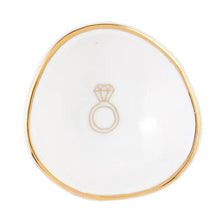 Load image into Gallery viewer, The Ring Dish is a small, elegant white ceramic bowl with an asymmetrical shape and gold-accented rim. It showcases a minimalist design with a simple gold outline of a diamond ring at the center, perfect for stylishly storing your rings. Ideal for those who value refined style in ceramics.
