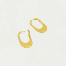 Load image into Gallery viewer, Two gold, oval-shaped hoop earrings, called Crosby Hinged Hoops, are displayed on a light background. These 18kt brushed gold earrings have curved edges with a sleek open-ended design, offering a modern and minimalist look.
