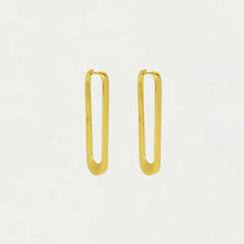 Load image into Gallery viewer, The Crosby Drop Hoops, crafted from 18kt gold, hang elegantly with a sleek, minimalistic design. Inspired by New York architecture, these elongated earrings feature rounded corners and a polished finish that casts subtle shadows against a plain background.
