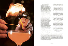 Load image into Gallery viewer, Close-up of hands holding a matchstick, lighting a cigar. In the foreground, a cocktail crafted from &quot;The Bartender&#39;s Manifesto&quot; with a frothy top takes center stage. The opposite page delves into text about experiences and curiosity, emphasizing comfort. Soft lighting creates a warm, inviting atmosphere.
