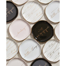 Load image into Gallery viewer, The &quot;Trinket Tray - Little Things&quot; collection includes small square ceramic trays with rounded edges and metallic gold rims. Featuring cursive text like &quot;darling,&quot; &quot;pretty little things,&quot; and &quot;c&#39;est magnifique,&quot; the trays come in black, white, and pale pink with an artful overlapping pattern.
