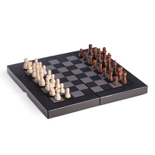 Load image into Gallery viewer, Experience strategic fun with the Backgammon/Chess Set 15.5&quot; Wood W/ &quot;Carbon Fiber,&quot; featuring a foldable checkered board design. It highlights alternating black and gray squares, divided by a fold line on an elevated textured surface, and comes with light wooden pieces on the left and dark ones on the right.
