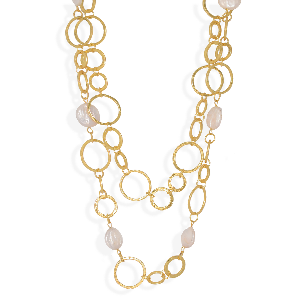 The Pearls and Chain Multi Layer Statement Necklace is a sophisticated piece showcasing a series of interlocking oval links in textured gold, varying in size. Interspersed along the chain are lustrous, irregularly shaped freshwater pearl beads that enhance its texture and provide a captivating contrast, resulting in an elegant and contemporary design.