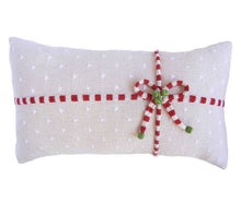 Load image into Gallery viewer, The Gift Lumbar Pillow, Ecru, is a handmade rectangular creation showcasing white polka dots and embellished with a red and white knitted striped ribbon tied into a bow, accentuated with small green leaves. Its design radiates a festive holiday charm inspired by traditional Armenian crafts.
