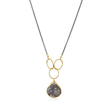 Load image into Gallery viewer, The Cassiopeia Necklace boasts a black gold-filled chain and features a pendant of interlinked gold loops, which elegantly hold a textured, irregularly shaped stone. This modern design beautifully showcases the stone in its gold setting at the base of the loops and is prominently displayed against a white background.
