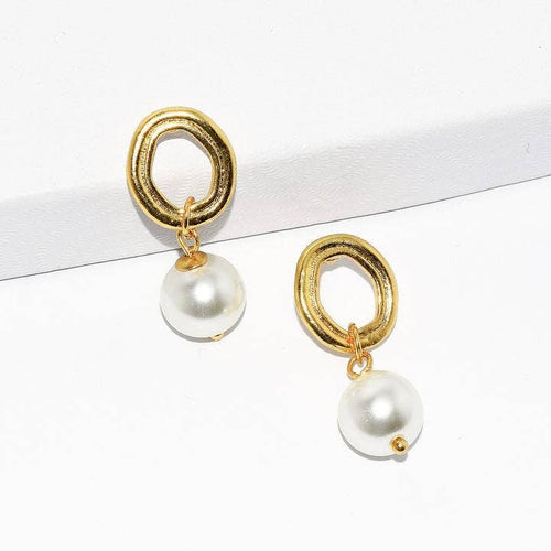 The Oblong Frame Pearl Drop Earrings are showcased with their gold-plated, irregular oval shapes reflecting a regency style. Each earring is adorned with a round, lustrous pearl drop that dangles below the hoop, resting on a simple white surface to highlight their elegance and simplicity.