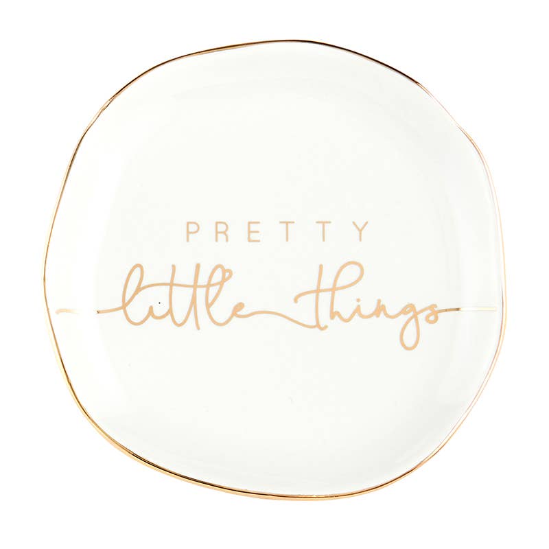 The Trinket Tray - Little Things is a charming, small white ceramic dish with a slightly irregular round shape. It features "Pretty little things" in elegant light brown script and is accented with a metallic gold rim for added elegance.