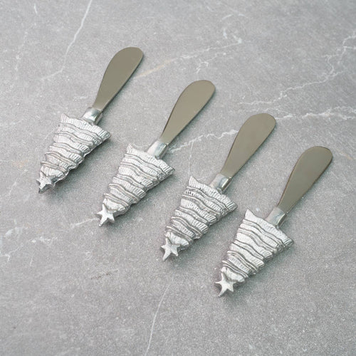 A set of four Christmas Tree Spreaders is artfully arranged diagonally on a textured gray surface, featuring handles shaped like festive trees with a star on top and horizontal lines creating a layered design. Ideal for any holiday gathering.