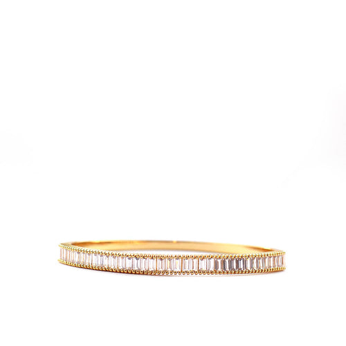 The Sterling Baguette CZ Hinged Bangle features a gold bracelet with geometric rectangular segments adorned with sparkling stones, set against a white background to highlight its elegance and reflective details.