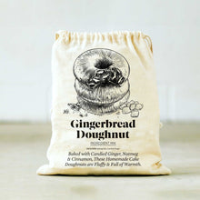 Load image into Gallery viewer, The Gingerbread Doughnut Baking Mix &amp; Mold Set includes a beige drawstring bag adorned with an illustration of stacked doughnuts and marked &quot;Gingerbread Doughnut Ingredient Mix.&quot; The text below highlights that the mix is crafted with candied ginger, nutmeg, and cinnamon to make fluffy homemade cake doughnuts infused with warmth. Perfect for pairing with a silicone doughnut mold on a minimalist background.
