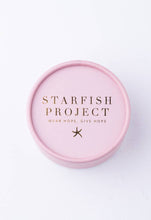 Load image into Gallery viewer, The round, light pink box prominently displays &quot;Starfish Project&quot; in elegant gold letters on its lid. Just below, the phrase &quot;Wear Hope, Give Hope&quot; is accompanied by a small starfish icon. Opening the box reveals the stunning Give Hope Earrings, plated in 14K gold that shines beautifully against a simple white surface.
