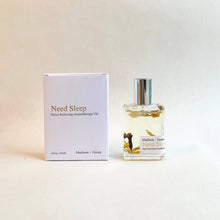 Load image into Gallery viewer, A glass bottle of the &quot;Need Sleep&quot; Aromatherapy Body Oil is positioned next to its white box packaging. Both the label and box prominently feature the phrases &quot;Therapeutic Aroma&quot; and &quot;Madison + Green.&quot; Enriched with organic essential oils, this blend showcases delicate botanicals floating within a neutral backdrop.
