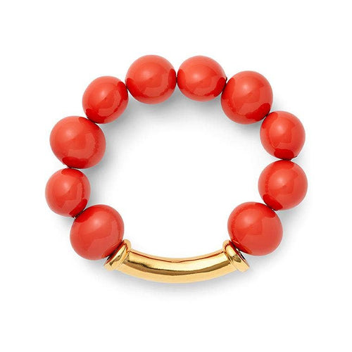 Introducing the Pebble Pearl Bracelet, showcasing an elegant arrangement of large, glossy coral beads in a circular design. A smooth, curved 14 karat golden metal bar acts as a clasp, beautifully connecting the beads into a seamless loop. This simple yet sophisticated piece blends vibrant red with luxurious gold accents.