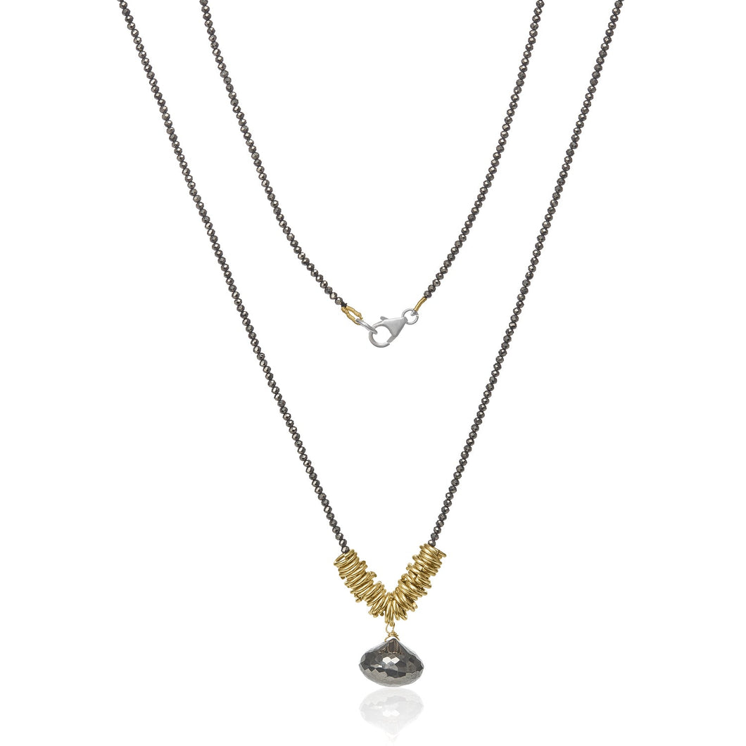 The Eden’s Pyrite Apple Necklace features a beautiful handcrafted design with two layers. The lower layer showcases a series of small gold-filled rings arranged in a V shape, complemented by a dangling teardrop-shaped metallic pendant. Slender, dark chains and a silver lobster clasp enhance the elegance of this stunning accessory.