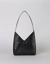 Load image into Gallery viewer, Introducing the Vicky Bag - Classic Leather: a sophisticated black shoulder bag with a minimalist and vintage geometric design. Made from eco-friendly leather, it features a singular strap and distinct triangular shape enhanced by its smooth, glossy finish. The plain light grey background accentuates the bag&#39;s elegant and contemporary style.
