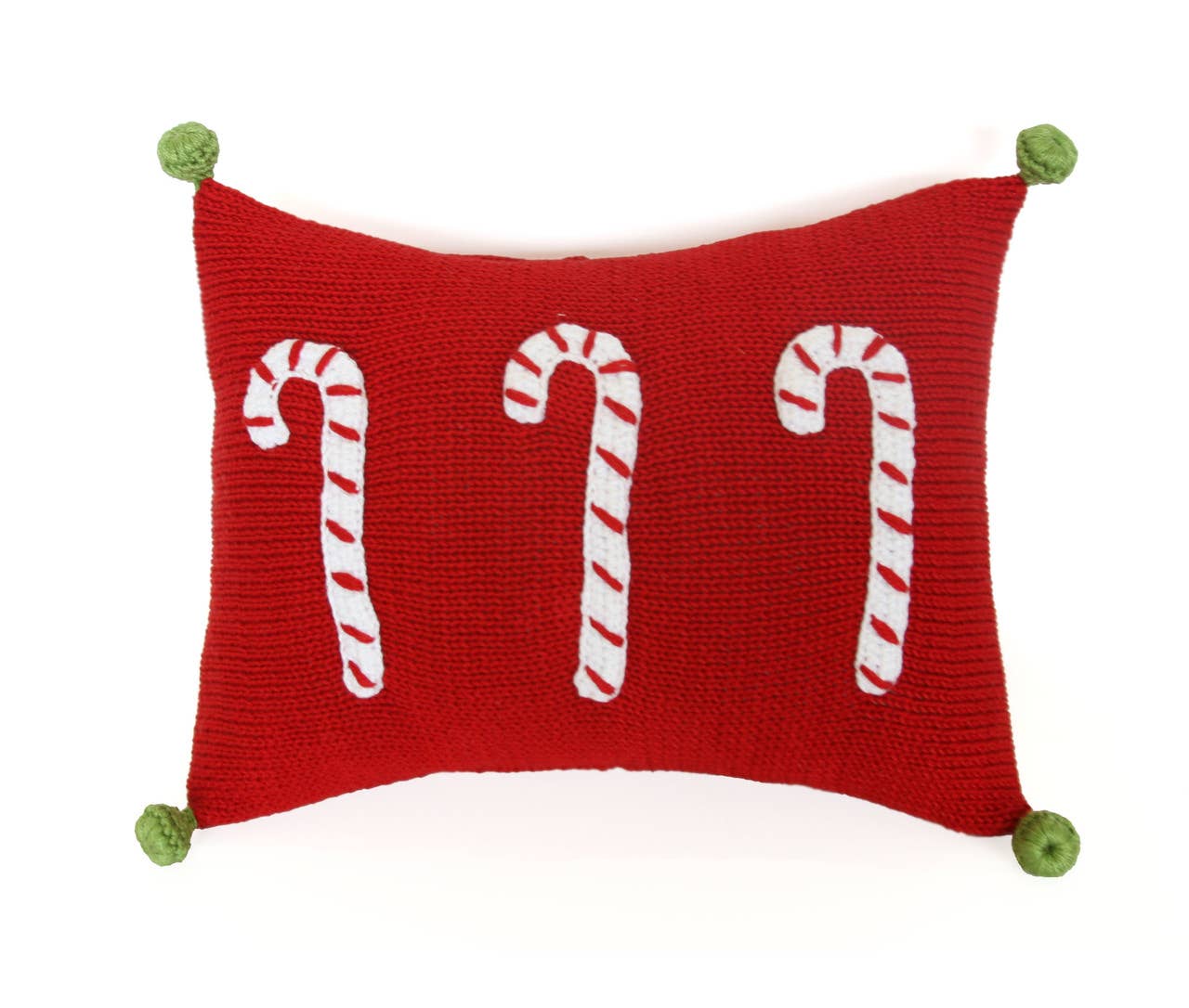 The Candy Cane Mini Pillow in red is a rectangular, handmade piece featuring three white-and-red striped candy canes knit into its design. Each corner is adorned with a small green, textured knob that resembles knitted tassels, ensuring the candy canes are evenly spaced for a balanced appearance. This product is fairly traded.