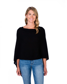 A smiling woman with long blonde hair is wearing the Cashmere Poncho, a stylish black poncho that elegantly tops her blue jeans. She stands against a simple white background. This one-size garment has a wide neckline and drapes loosely down her arms, giving off a relaxed and casual vibe.