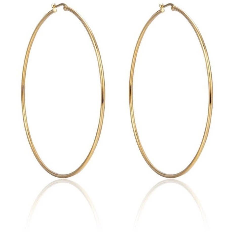 Introducing the Oval Hula Hoops: large, gold-plated hoop earrings featuring a smooth, polished finish. These tarnish-resistant earrings are symmetrically designed with a simple clasp closure at the top. Positioned vertically against a white background, their faint shadow offers an elegant reflection.