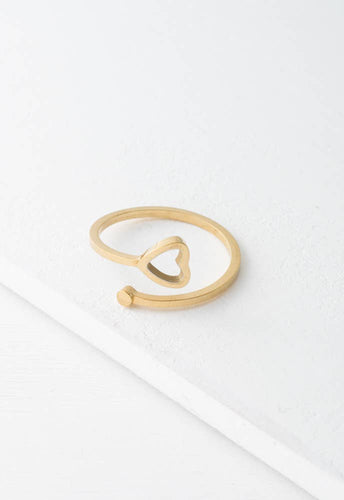 The Ada Gold Heart Ring is designed with an open band, combining elegance and minimalism. It features a small heart on one end and a round bead on the other, making it adjustable for the perfect fit. Displayed on a white surface, this hypoallergenic gold ring brilliantly showcases simplicity and charm.